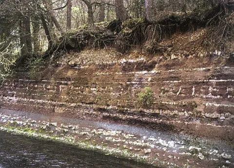 Podmytý breh rieky Eyach s odkrytými horninami keuperu v meste Balingen (miestna časť Ostdorf), Nemecko
